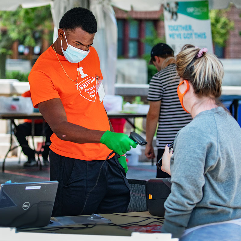 students submit saliva samples as part of a COVID-19 test at a testing tent outside Foellinger Auditorium