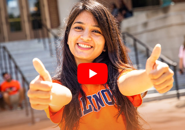 student giving a thumbs up in front of Foellinger Auditorium