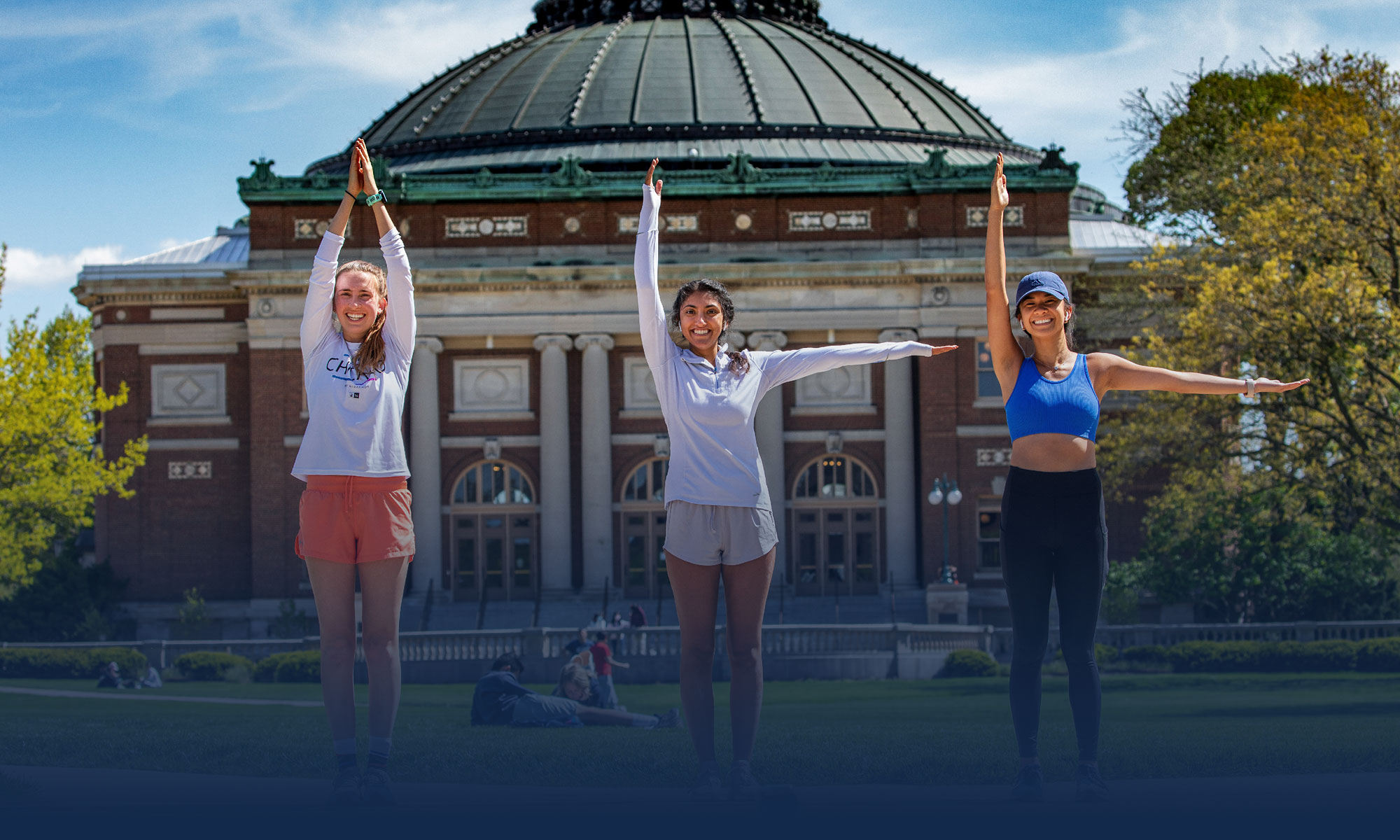Illinois students on the Quad in front of Foellinger Auditorium spelling I-L-L with their arms