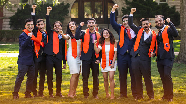 graduates celebrating with fists in the air on the Quad