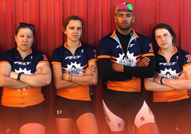 Illini 4000 team members posing together in their bike jerseys leaning on a bright red wall
