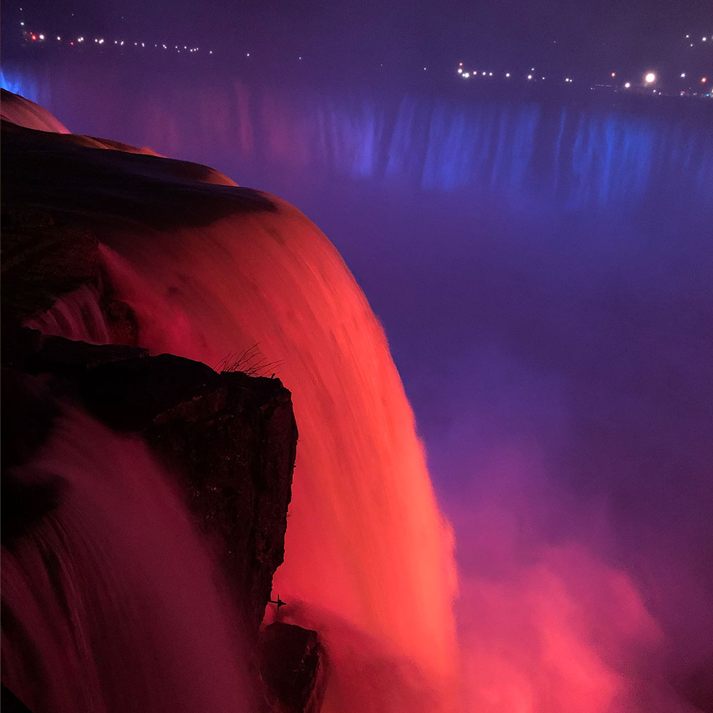 Niagra Falls lit up in orange & blue