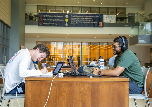 two friends study together at a communal table in the ECE building
