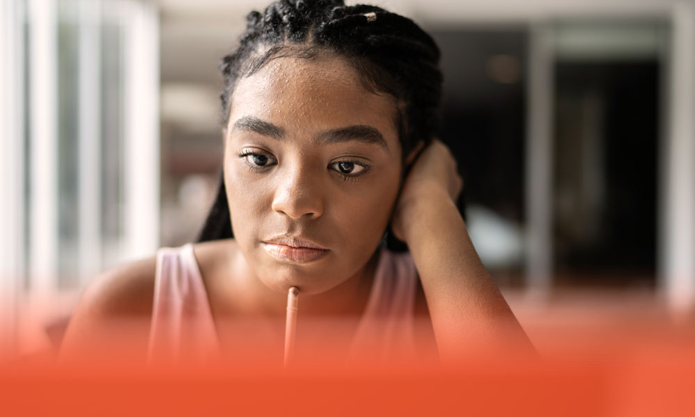 female high schooler studying on her laptop, pencil to her chin