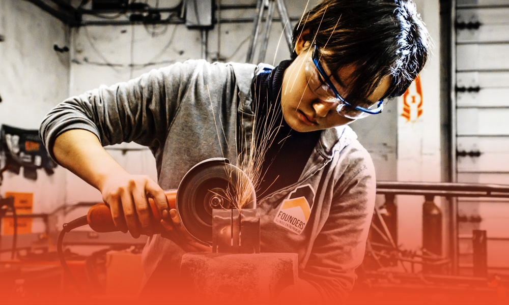 undergraduate mechanical science and engineering student uses a grinder at the Engineering Student Project Lab in the College of Engineering