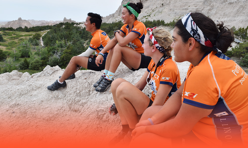 Julissa and her Illini 4000 teammates sitting on a rockface looking out over a valley