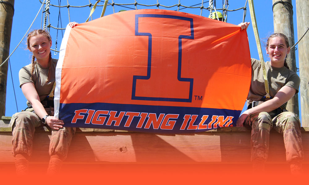 ROTC students hold a Fighting Illini flag at an obstacle course
