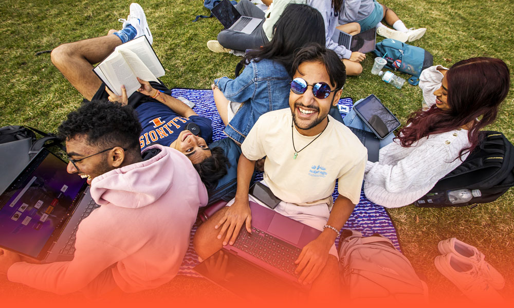 smiling group of friends studying together on the Quad and literally leaning on one another