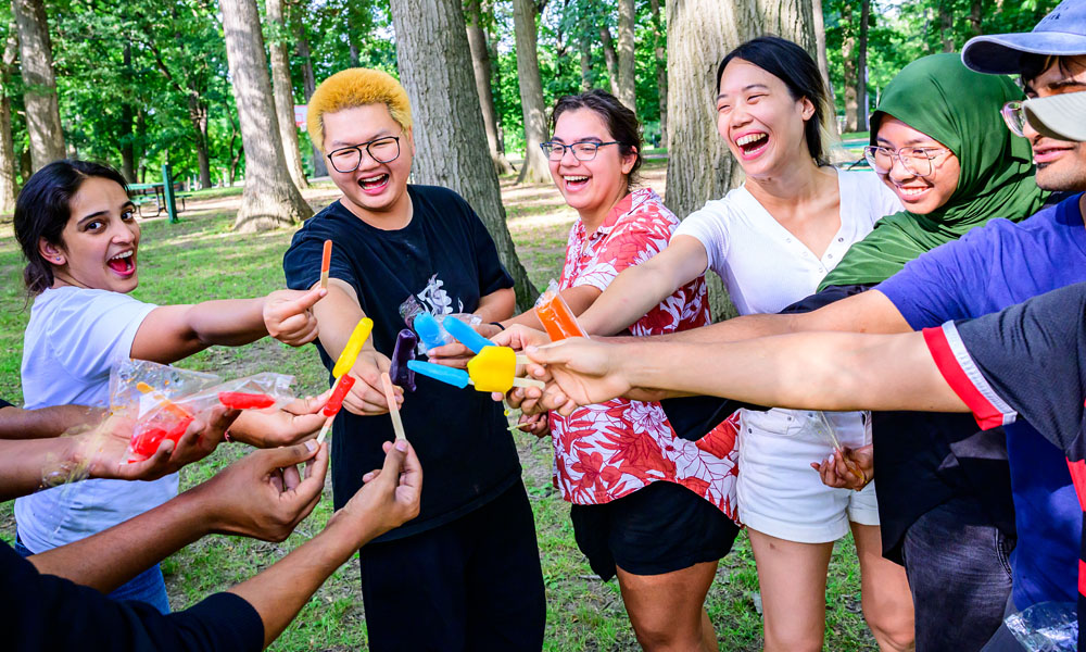 students huddle together with popsicles during a summer picnic event sponsored by Illinois internation support programs